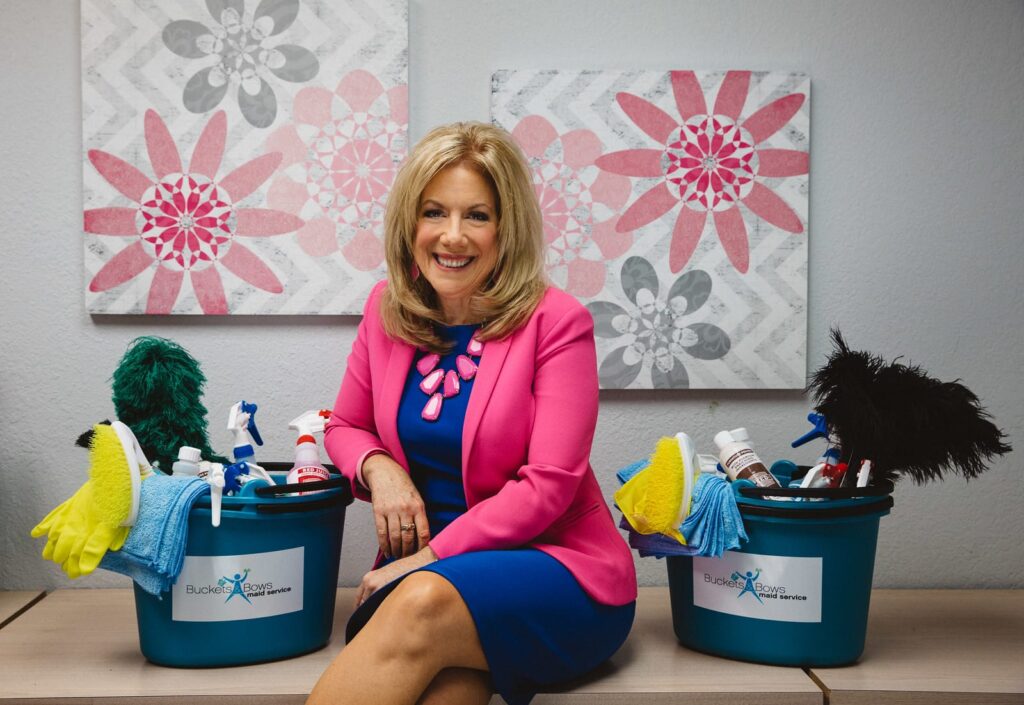 Debbie sitting on desk with cleaning products